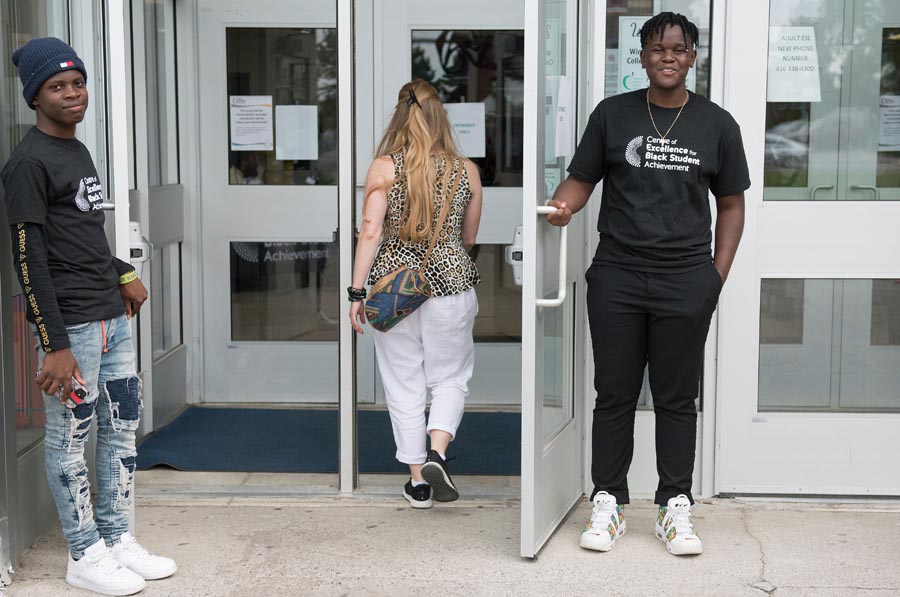 Student volunteers hold open a door for an attendee. Open Gallery